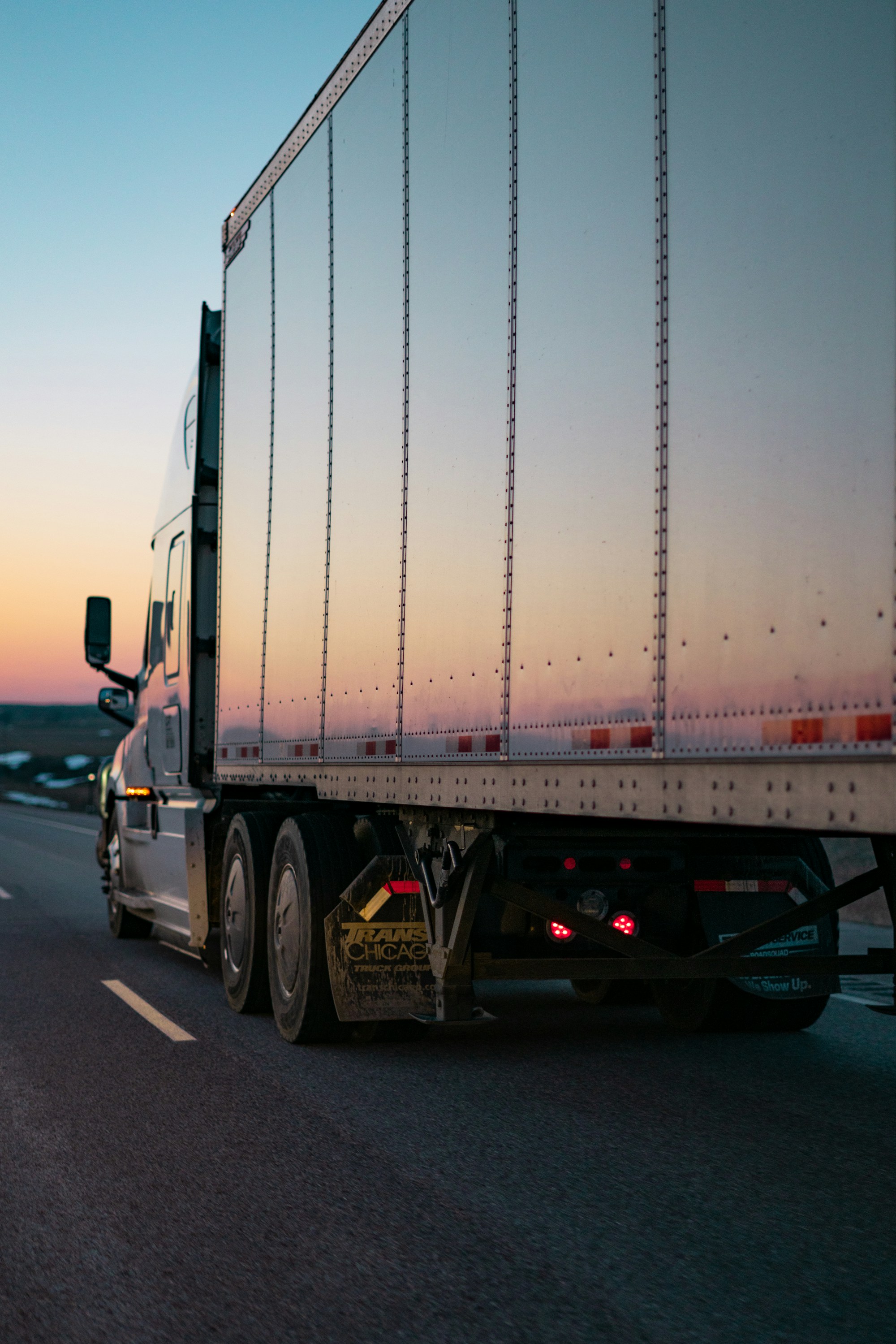 White semi truck on an open road at sunset